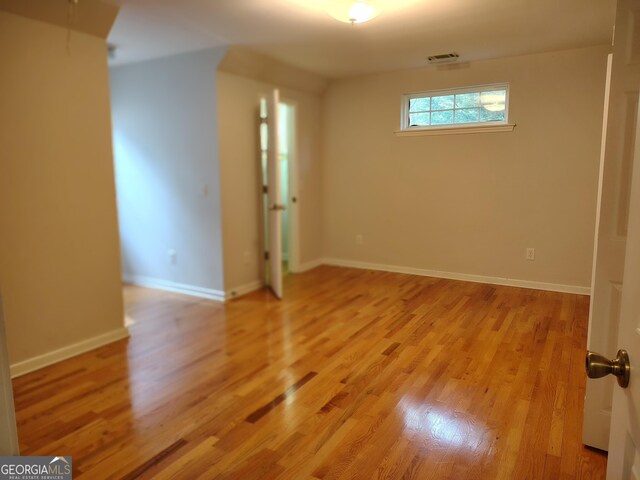 spare room with baseboards, light wood-type flooring, and visible vents