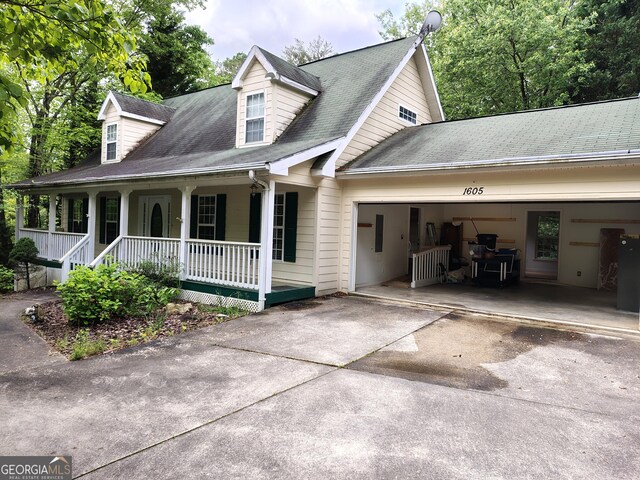 view of front of property featuring a porch, roof with shingles, a garage, and driveway