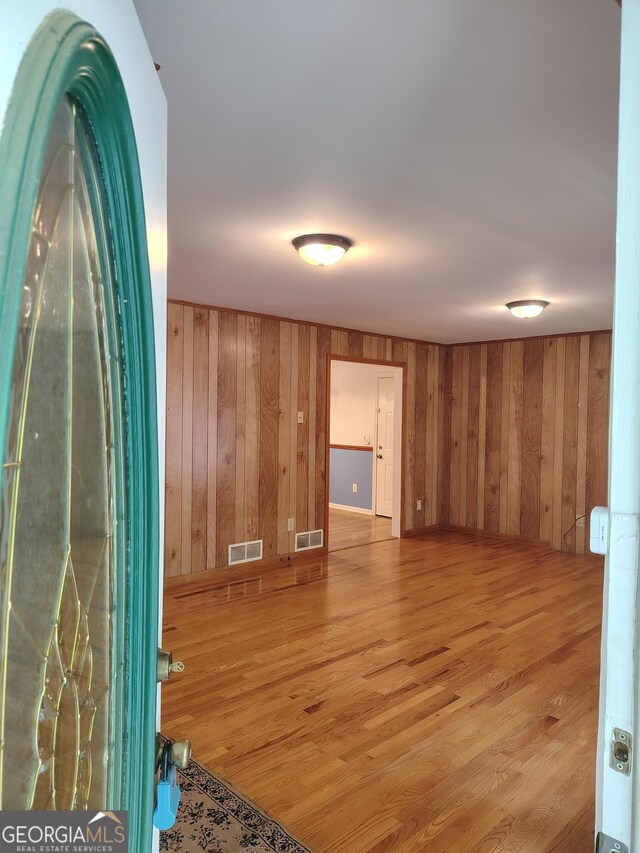 spare room with wooden walls, visible vents, and wood finished floors