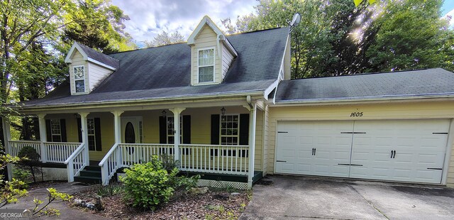 new england style home with a porch, concrete driveway, and an attached garage