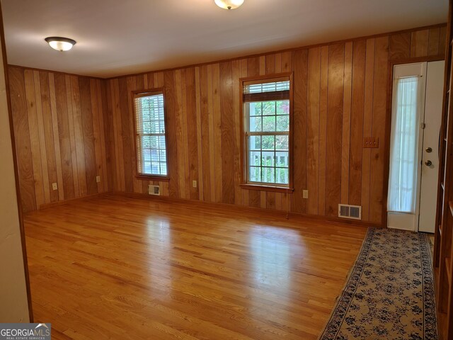 spare room featuring wooden walls, visible vents, and wood finished floors