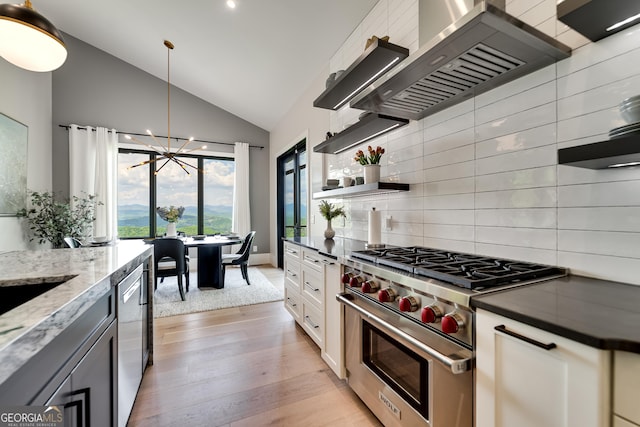 377 Charmont Dr, Tiger, GA 30576 - kitchen with stainless steel appliances, wall chimney exhaust hood, vaulted ceiling, an inviting chandelier, and light wood finished floors