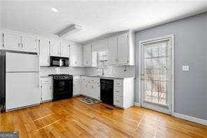 kitchen with freestanding refrigerator, black dishwasher, stove, and wood finished floors