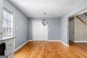unfurnished dining area with stairway, an inviting chandelier, baseboards, and light wood-style floors