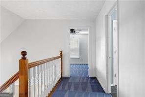 hall featuring an upstairs landing and lofted ceiling