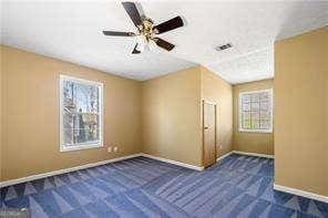 bonus room with baseboards, dark carpet, and a healthy amount of sunlight