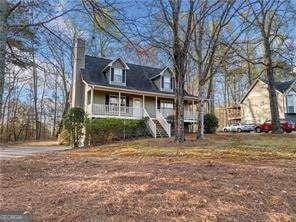 new england style home featuring a porch, stairs, and a chimney