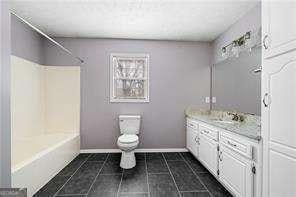 bathroom featuring toilet, shower / washtub combination, tile patterned floors, baseboards, and vanity