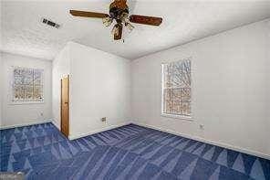 spare room featuring visible vents, baseboards, ceiling fan, and carpet floors