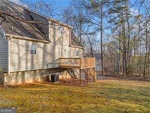 rear view of house with a lawn, stairway, and a wooden deck