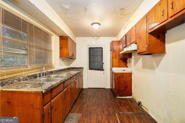 1491 Boulderwoods Dr, Atlanta, GA 30316 - kitchen featuring under cabinet range hood, baseboards, a sink, dark wood-type flooring, and brown cabinets