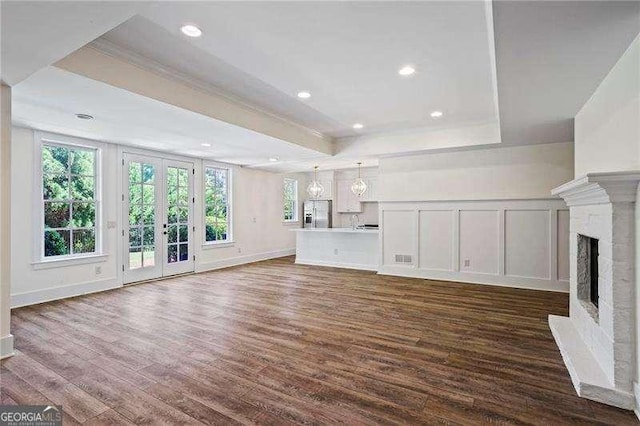13922 Tree Loft Rd, Milton, GA 30004 - unfurnished living room featuring french doors, crown molding, dark wood-type flooring, a raised ceiling, and a fireplace with raised hearth