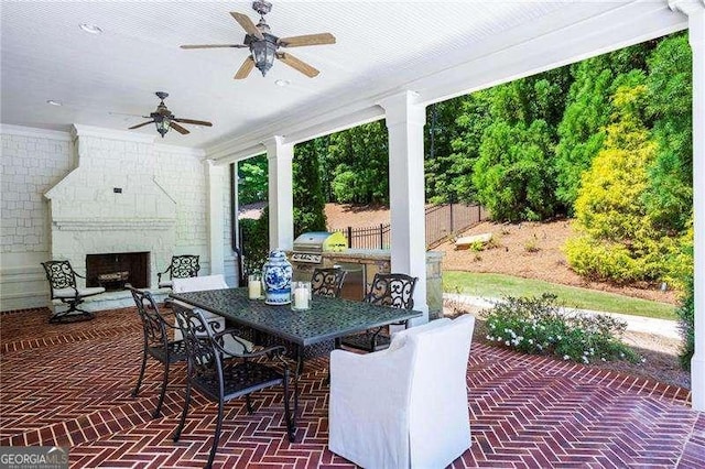 13922 Tree Loft Rd, Milton, GA 30004 - view of patio featuring fence, exterior kitchen, outdoor dining space, a large fireplace, and ceiling fan