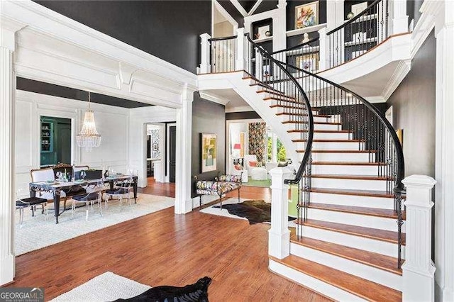 13922 Tree Loft Rd, Milton, GA 30004 - stairway featuring ornamental molding, a chandelier, a high ceiling, and wood finished floors