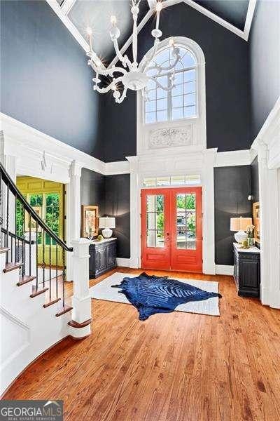 13922 Tree Loft Rd, Milton, GA 30004 - foyer featuring high vaulted ceiling, french doors, wood finished floors, stairway, and a chandelier