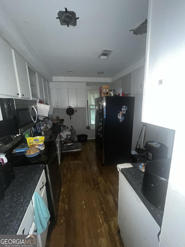 1621 Lee St, Brunswick, GA 31520 - kitchen featuring freestanding refrigerator, dark wood-style floors, dark countertops, white cabinets, and stainless steel electric stove