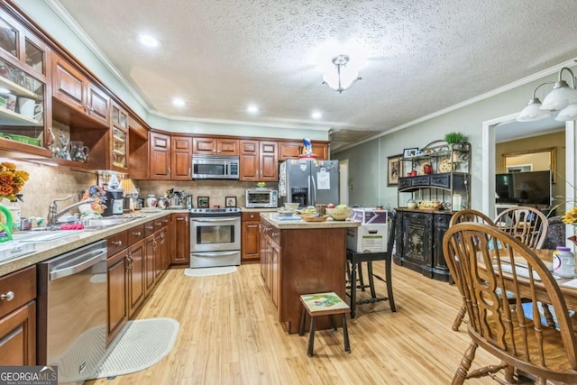 292 Lumpkin St, Winder, GA 30680 - kitchen with stainless steel appliances, light wood-style flooring, crown molding, and a textured ceiling