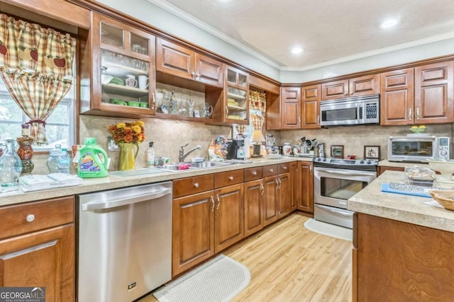 292 Lumpkin St, Winder, GA 30680 - kitchen featuring brown cabinets, a sink, stainless steel appliances, light countertops, and ornamental molding