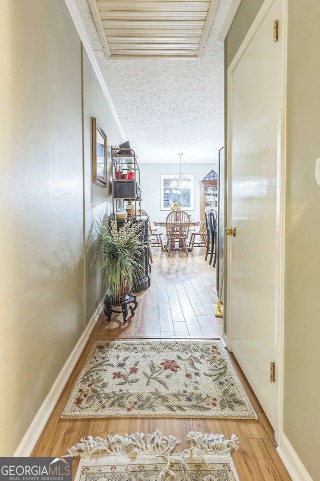 292 Lumpkin St, Winder, GA 30680 - corridor featuring baseboards, a notable chandelier, a textured ceiling, and wood finished floors