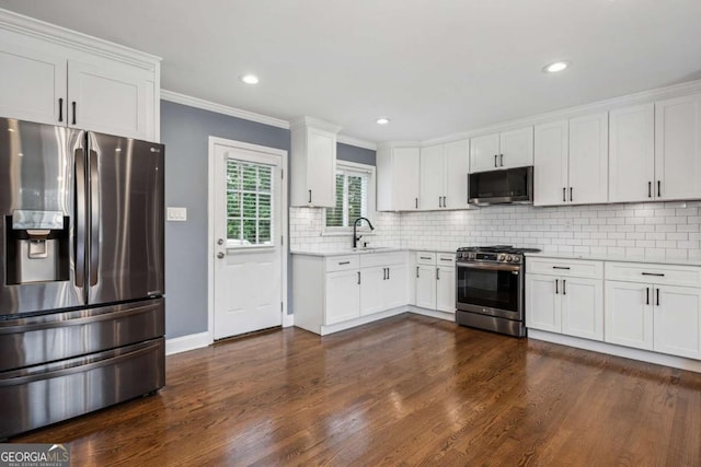 kitchen with stainless steel appliances, dark wood-style flooring, light countertops, decorative backsplash, and white cabinets