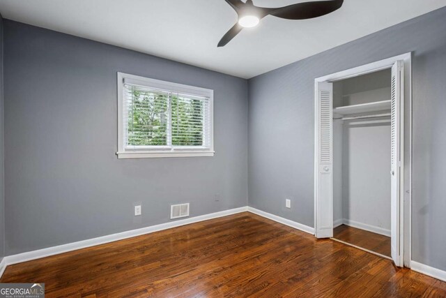 unfurnished bedroom featuring dark wood-style flooring, baseboards, a closet, and visible vents