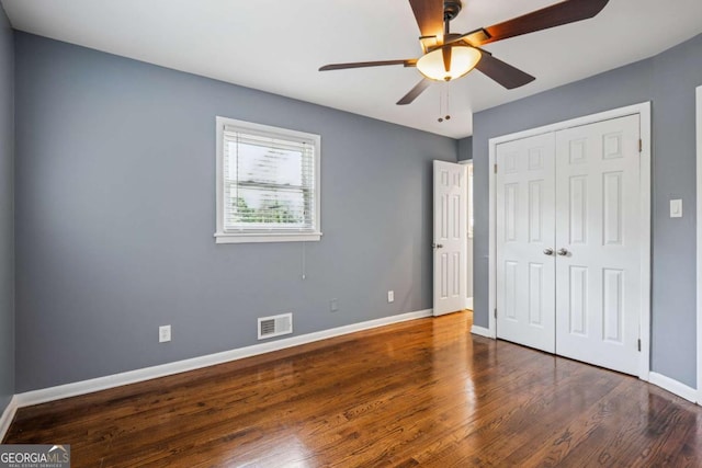unfurnished bedroom featuring a closet, wood finished floors, visible vents, and baseboards