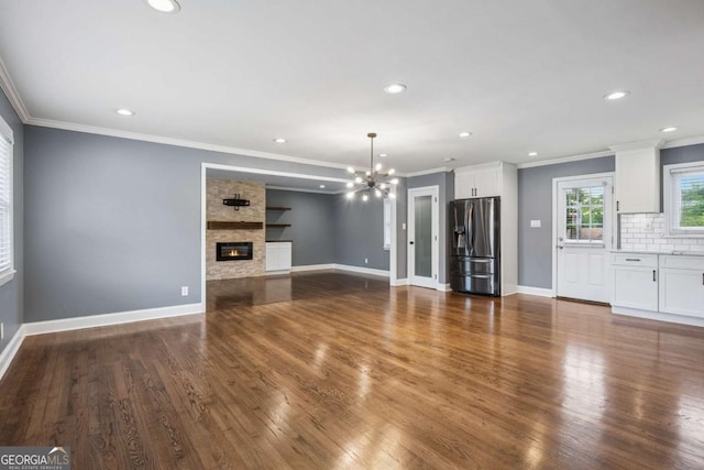 unfurnished living room with an inviting chandelier, ornamental molding, and recessed lighting