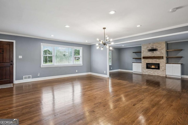 unfurnished living room featuring crown molding, visible vents, dark wood-type flooring, a stone fireplace, and a chandelier