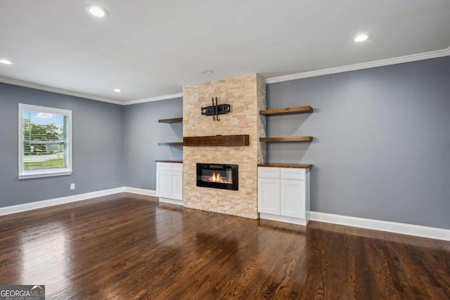 unfurnished living room featuring recessed lighting, baseboards, a stone fireplace, ornamental molding, and dark wood finished floors