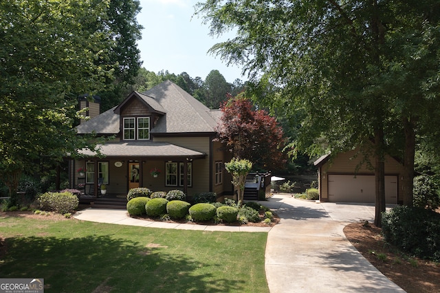 craftsman-style house featuring covered porch, driveway, an outbuilding, a front yard, and a chimney