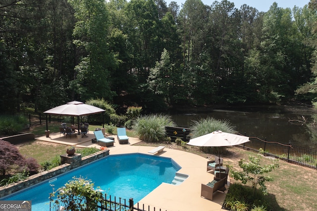 view of swimming pool featuring a diving board, a fenced in pool, fence, a water view, and a patio area