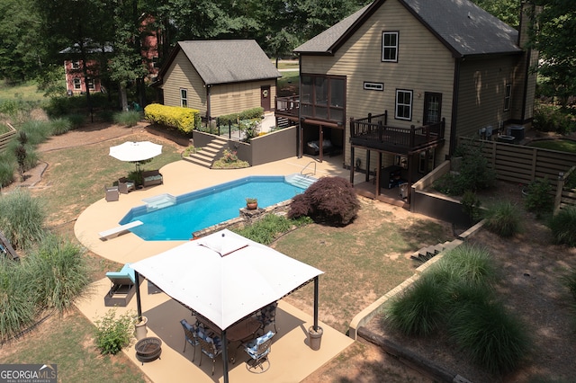 outdoor pool featuring a diving board, fence, a patio area, stairway, and a wooden deck