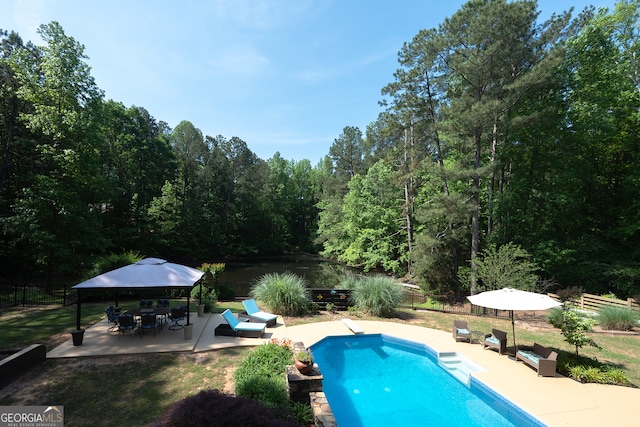 view of pool with a patio area, a view of trees, a fenced in pool, and a fenced backyard