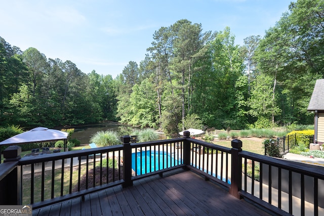 wooden terrace featuring a forest view and an outdoor pool