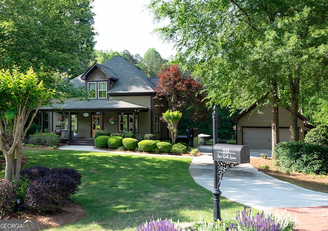 craftsman inspired home featuring an outbuilding, a front lawn, a porch, roof with shingles, and a detached garage