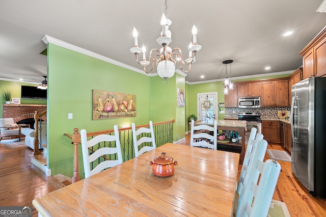 dining room featuring crown molding, light wood-style flooring, ceiling fan with notable chandelier, and recessed lighting