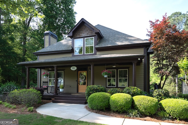craftsman house featuring a chimney, a shingled roof, and covered porch