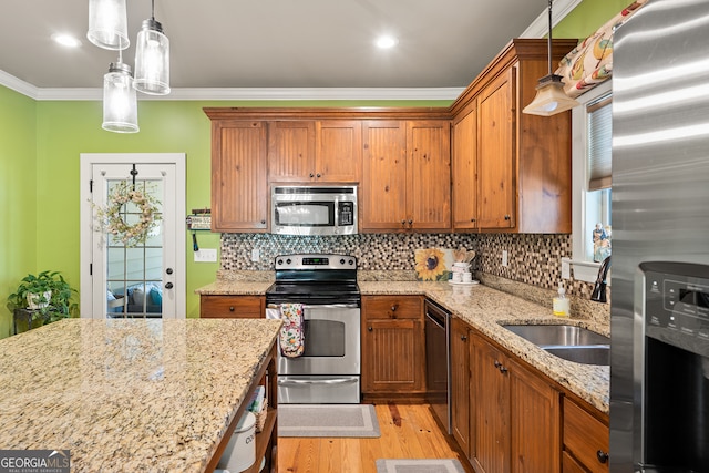 kitchen with a sink, stainless steel appliances, tasteful backsplash, crown molding, and light wood-style floors