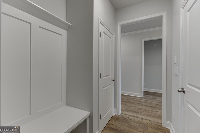 mudroom featuring crown molding, wood finished floors, and baseboards