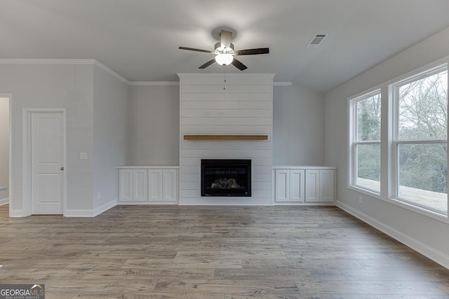 unfurnished living room with wood finished floors, visible vents, baseboards, ceiling fan, and a large fireplace