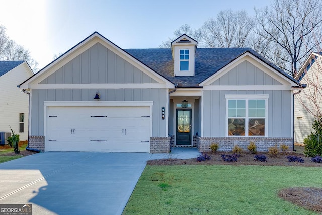 craftsman-style house with board and batten siding, driveway, brick siding, a shingled roof, and a front yard