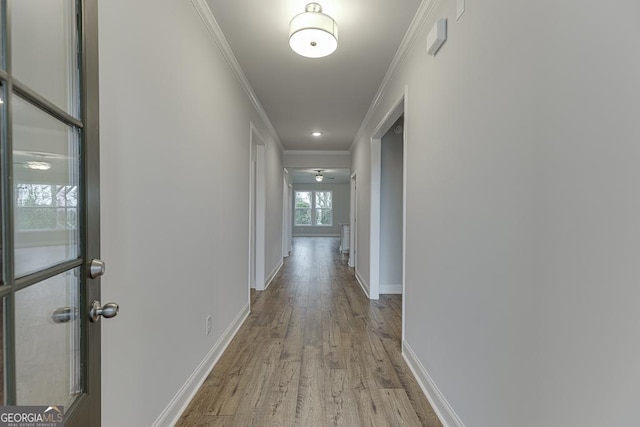 hallway with baseboards, ornamental molding, and wood finished floors