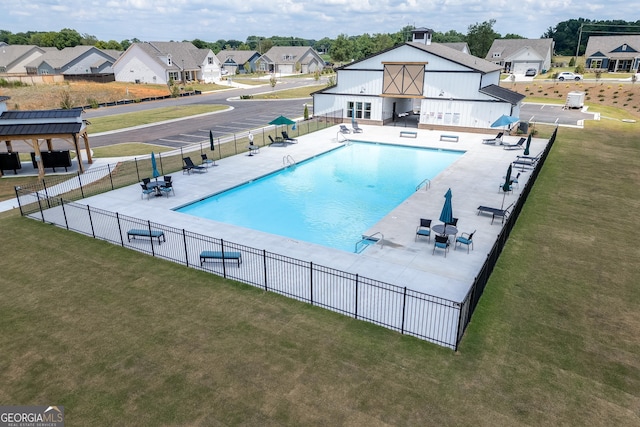community pool with a yard, fence, a patio area, and a residential view