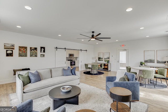 living area featuring light wood-type flooring, a barn door, and recessed lighting