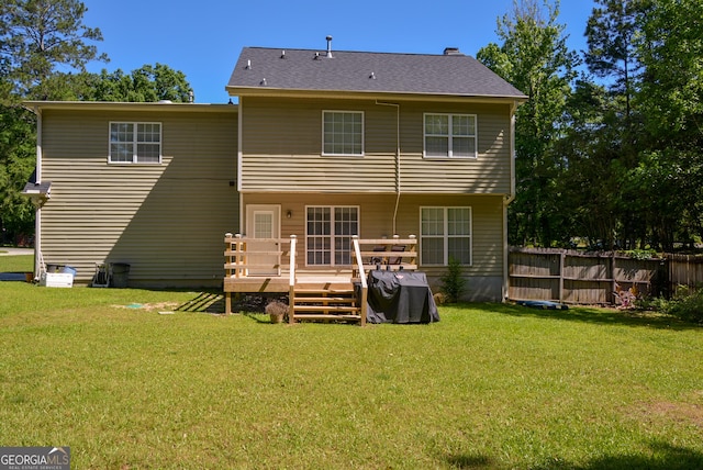 rear view of house featuring a lawn, a deck, and fence