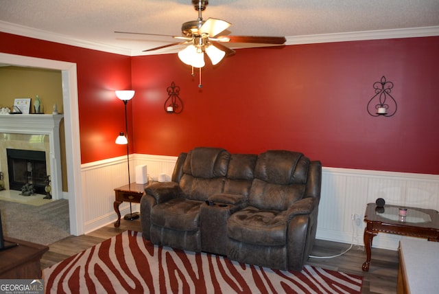 living area with crown molding, wainscoting, ceiling fan, and wood finished floors