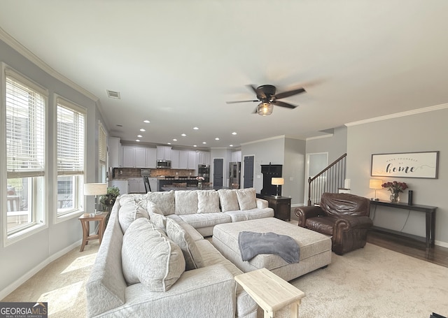 living room with baseboards, healthy amount of natural light, a ceiling fan, ornamental molding, and recessed lighting