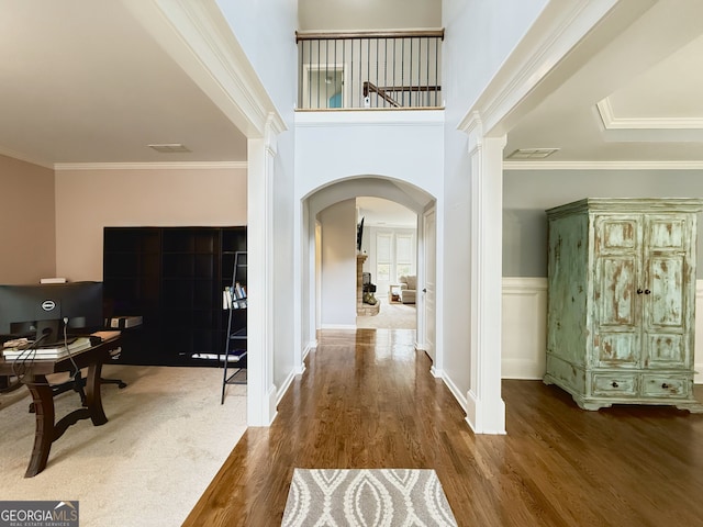 foyer entrance with arched walkways, wood finished floors, crown molding, and decorative columns