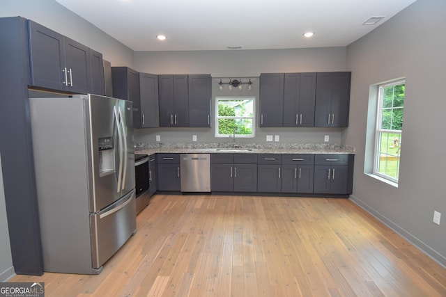 kitchen with appliances with stainless steel finishes, visible vents, light stone countertops, and a healthy amount of sunlight