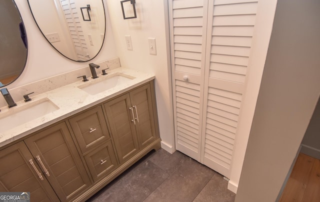 bathroom with double vanity, baseboards, and a sink